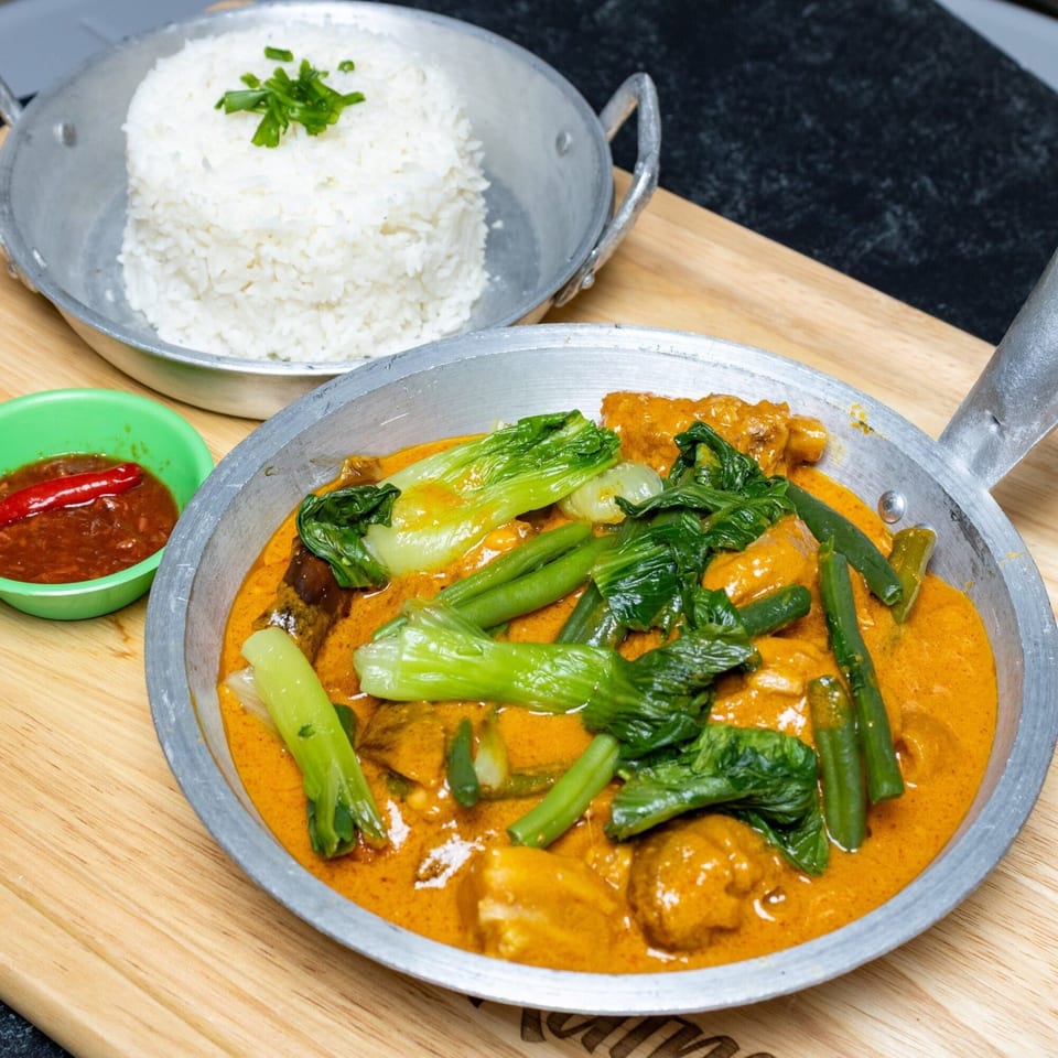 Filipino Kare-Kare with bok choy and green beans, served with white rice and chili sauce.